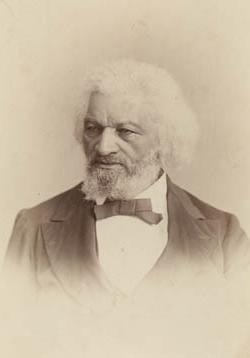 <p>Black and white photograph of a Black man with a black and white beard and white hair down to his ears facing the camera but looking to the right. He wears a black suit and bow tie. </p>