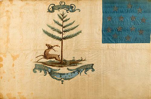 <p>A flag painted on yellowing white silk, somewhat worn. In the upper lefthand corner is a square of blue silk with 13 stars arranged in a circle. In the center is a bounding stag beneath a pine tree. A large cartouche underneath, slightly peeling, reads “The Bucks of America,” smaller cartouche at the top of the image has the initials “J-G-W-H.” painted in gold.</p>